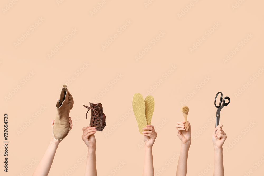 Female hands with shoe, scissors and insoles on beige background. Shoes repair concept