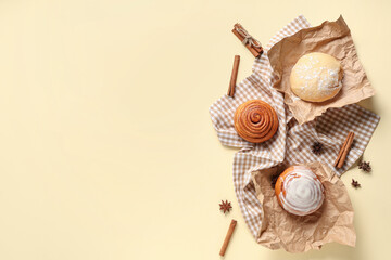 Wall Mural - Buns with dough, napkin and cinnamon sticks on light yellow background