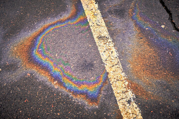 Oil, gasoline, or oil spill on wet asphalt with a parking lot and a dividing line.