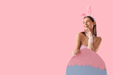 Sticker - Sexy young woman in bunny ears with big paper Easter egg on pink background