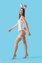 Wall Mural - Sexy young woman in bunny ears on blue background. Easter celebration