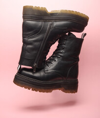 Wall Mural - Black leather boots floating on pink background