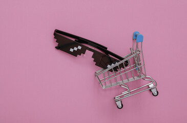 Wall Mural - Pixelated 8 bit sunglasses in shopping cart on pink background