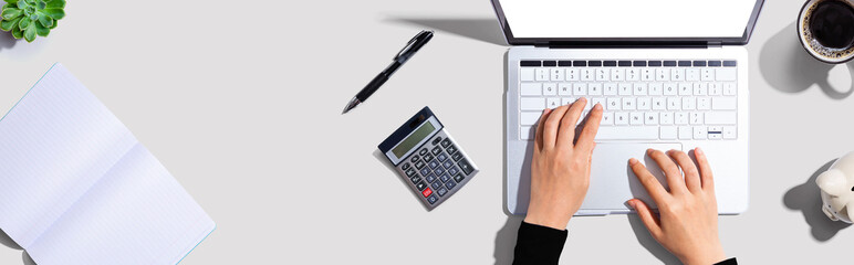 Poster - Woman using a laptop computer with a piggy bank and a calculator