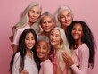 © Andrey - A group of women, spanning different age ranges and cultural backgrounds, pose together to celebrate unity and the multifaceted beauty of multiple generations on a pink background.