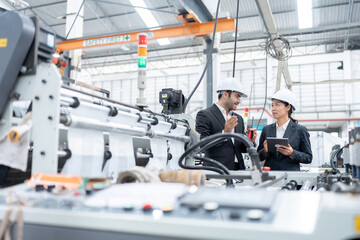 Wall Mural - European male engineer and Asian female senior official Owners and business partners of industrial plants Wear a suit to talk and inspect the operation of plastic and steel export production machinery