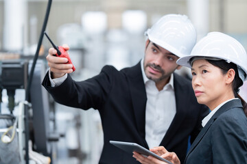 Wall Mural - Close-up of senior officials Asian woman holding tablet and looking at project next to European male architectural engineer Wear a suit and safety helmet. In steel and plastic export industries
