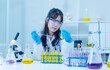 Asian young woman female laboratory assistant professional scientist  concentrated in a white lab coat and protective eyeglasses making test tubes research medicine experiments in chemical lab