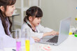 Asian woman teacher and little children girl reading laptop computer for data learning science at chemical laboratory study room. Education research and development concept learning for kids.