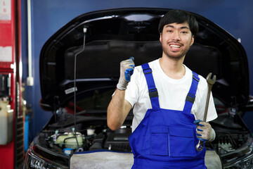 Wall Mural - mechanic raise hand celebrate win pose and holding wrench for fixing a car in automobile repair shop