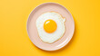 A fried egg on a yellow plate on a yellow background.