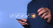© Alek - Male businessman ticks a green check mark In the checkbox to answer the questionnaire checklist for the Customer Experience Survey evaluation of feedback feedback.