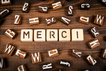 Wall Mural - Thank you in French. Alphabet blocks on wood texture background