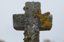 Old Stone Cross Covered In Moss On A Grave In Cemetery.