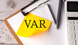 VAR word on yellow sticky with calculator, pen and clipboard