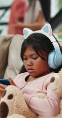 Wall Mural - Child, headphones and phone with couple fight on sofa while playing games, cartoon streaming and music in living room. Kid, smartphone and confused on couch with parents or argument in lounge of home