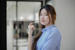 © SOMKID - Happy asian young businesswoman arms crossed standing in office working space.