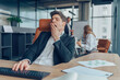 © Friends Stock - Young overtired businessman yawning while working inside modern office with computer