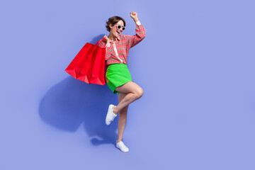 Wall Mural - Full size photo of overjoyed woman dressed print shirt hold new outfit in bags on shoulder dancing isolated on blue color background