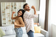© Home-stock - Young indian spouses dancing at home in living room, couple having fun, enjoying spending time together on weekend at home