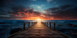 A dock with a sunset on the water, A bridge in the ocean with a sunset in the background. 

