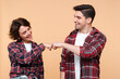 © Maria Vitkovska - Portrait of smiling couple wearing plaid shirts bumping fists isolated