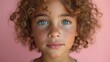 portrait of a blue eyes child with curly hair on pastel pink background 