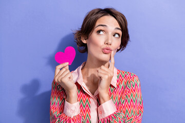 Poster - Photo portrait of attractive young woman hold pink heart look empty space dressed stylish print clothes isolated on purple color background