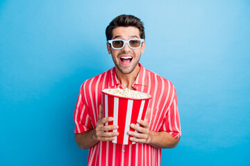 Sticker - Portrait of overjoyed funky guy wear stylish shirt in 3d glasses staring at funny comedy hold popcorn isolated on blue color background