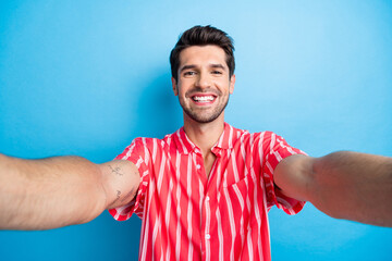 Sticker - Portrait of cheerful guy with stubble trendy haircut wear stylish shirt making selfie toothy smiling isolated on blue color background