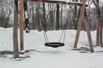 Wall Mural - Wooden playground made of natural eco-friendly material in public city park with snow at winter time. Modern safety children outdoor equipment. Winter activities. Children rest and games on open air