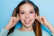 little girl grimacing and having fun at camera isolated over blue background.