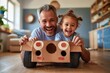 Smiling man and adorable child involved in fun play with a simple cardboard car indoors