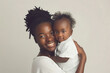© m - Afro-american smiling mother wear hijab hugging her sweet baby over white background. Child care, babyhood, motherhood. Products for children