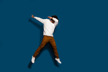 Poster - Full length photo of excited good mood guy dressed white pullover jumping high having fun empty space isolated dark blue color background