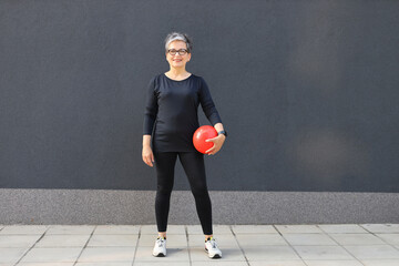 Poster - A Caucasian woman maintains her fitness through exercise, lifting weights in an indoor gym studio.