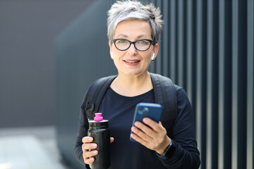 Poster - An active, fit Caucasian woman takes a break from outdoor training, holding a water bottle with a smile.