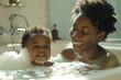 Afro-American mother bathing together with baby toddler. Cosy bathroom with natural light, mom and child playing with foam, happy and playful atmosphere. Hygiene for children, childcare. Daily routine