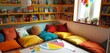 A snug reading nook in a children's room, with plush cushions and colorful storybooks neatly arranged.