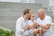 © Austockphoto - Boy with father and grandfather sitting on outdoor stairs