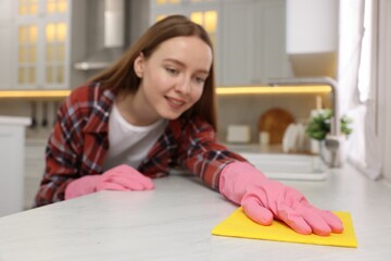 Sticker - Woman cleaning white marble table with microfiber cloth in kitchen, selective focus