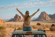A freedom-infused scene with a woman raising her hands atop a car roof, set against a vast desert landscape under a clear sky