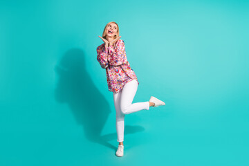 Sticker - Full length photo of girlish positive woman dressed print blouse white pants look at promo empty space isolated on teal color background