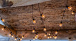 Light bulbs under a rustic wooden ceiling in a loft-style interior. Fashionable light in the interior. Lighting design. Suspended ceiling light in loft style, rustic style