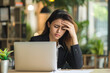 © AI_images - Overworked Latin woman having acute headache while working in office due to frustration, fatigue and crisis.