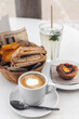 Coffee with milk, ham and cheese toast with chips, glass of lemonade and pastel de nata.