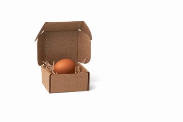 Chicken egg in cardboard box with paper filling on white background. Copy space.