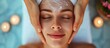 © Sona - An attractive young woman gets a facial massage at a spa from a high angle.