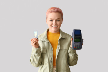 Poster - Young woman with credit card and banking terminal on light background