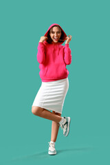 Young woman in fuchsia hoodie on green background